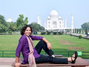 A woman in a purple tunic sits on a bench in front of the Taj Mahal, enjoying the serene view, representing the best way to visit Taj Mahal.