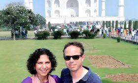 A couple smiles for a photo in front of the Taj Mahal, showcasing the best way to see this iconic monument