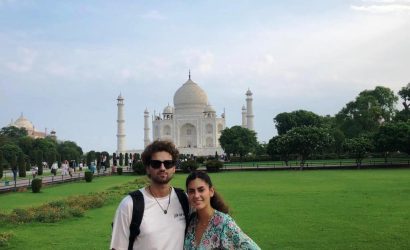 A young couple smiling in front of the Taj Mahal during their day trip from Jaipur to Taj Mahal.